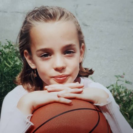 Emily Haine is posing with a basketball.